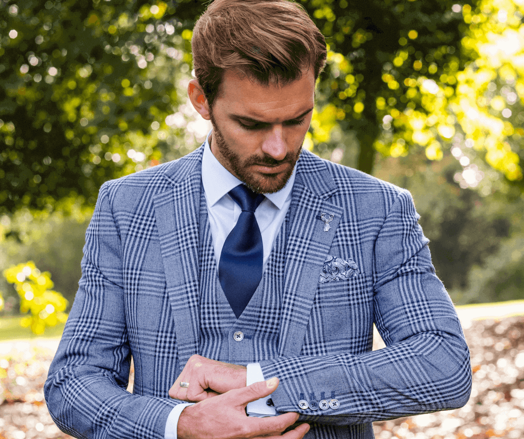 A model fixes the cuff on his checked suit jacket.