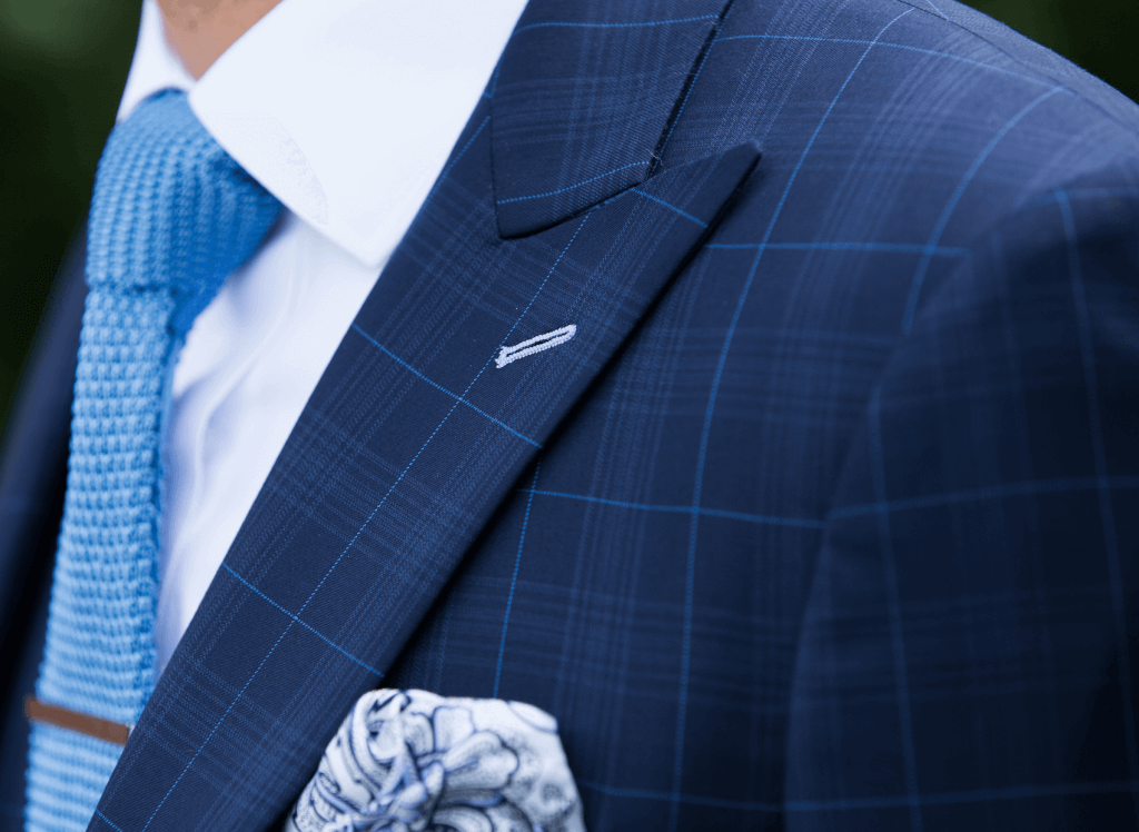 Close up shot of a patterned navy suit jacket with a mixed pattern tie and pocket square.