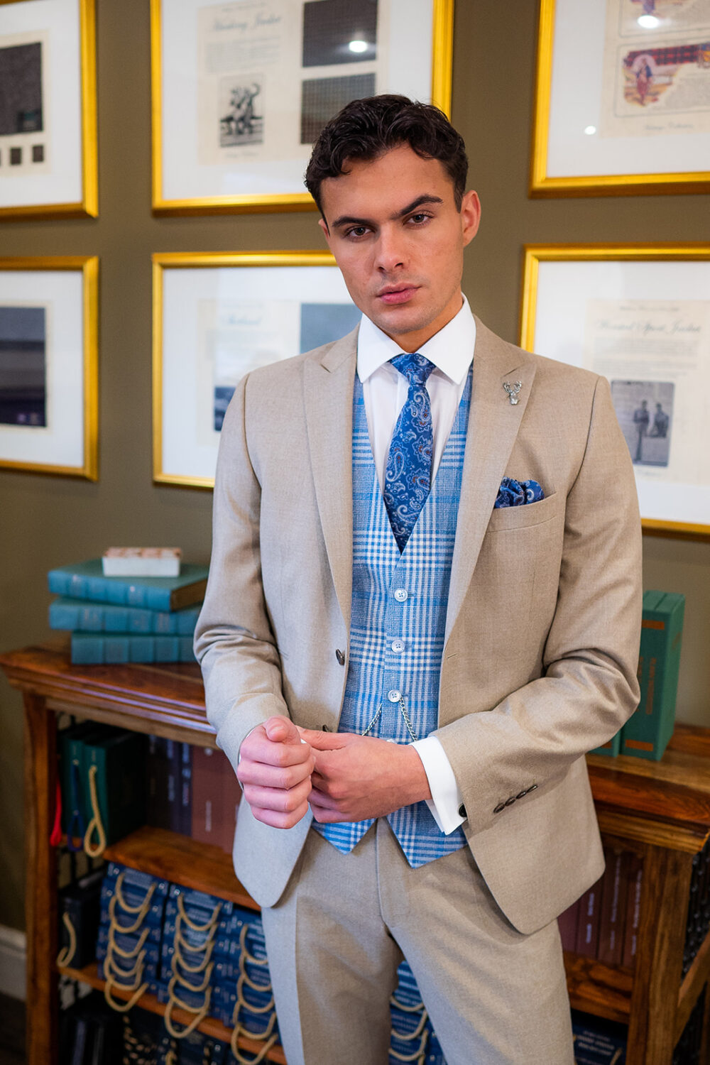 Slim fit beige suit in light weight, 100% wool. 3 piece beige suit with matching beige jacket, beige trousers and contrast light blue tweed single breasted waistcoat. Features a slim fit 2 button jacket with classic notch lapel. Worn with white French cuff shirt and coordinating blue silk tie and pocket square.