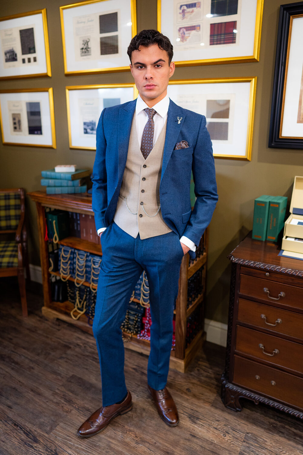Slim fit beige suit in light weight, 100% wool. 3 piece beige suit with matching beige jacket, beige single breasted waistcoat and contrast blue trousers. Features a slim fit 2 button jacket with classic notch lapel. Worn with white French cuff shirt and coordinating blue paisley silk tie and pocket square
