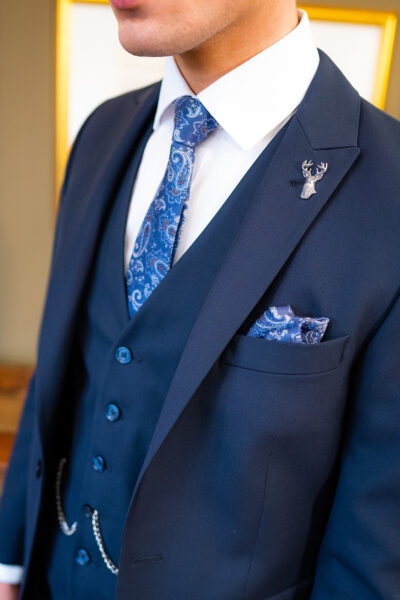 Slim fit navy suit in light weight, 100% wool. 3 piece navy suit with matching navy jacket, navy trousers and navy single breasted waistcoat. Features a slim fit 1 button jacket with classic peak lapel. Worn with white French cuff shirt and coordinating blue silk tie and pocket square.