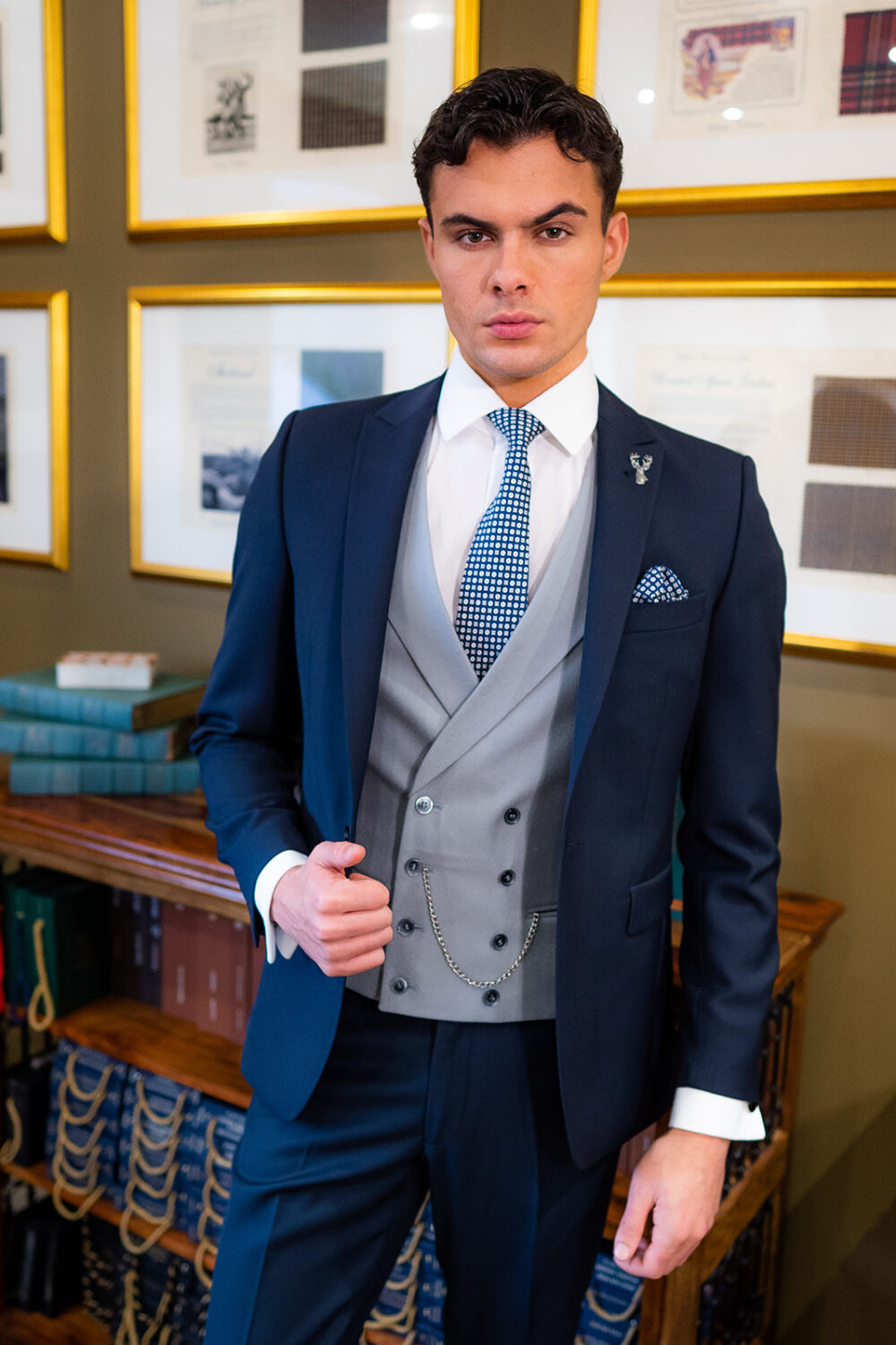 Slim fit navy suit in light weight, 100% wool. 3 piece navy suit with matching navy jacket, navy trousers and classic dove grey double breasted waistcoat. Features a slim fit 1 button jacket with classic peak lapel. Worn with white French cuff shirt and coordinating navy and white silk tie and pocket square.